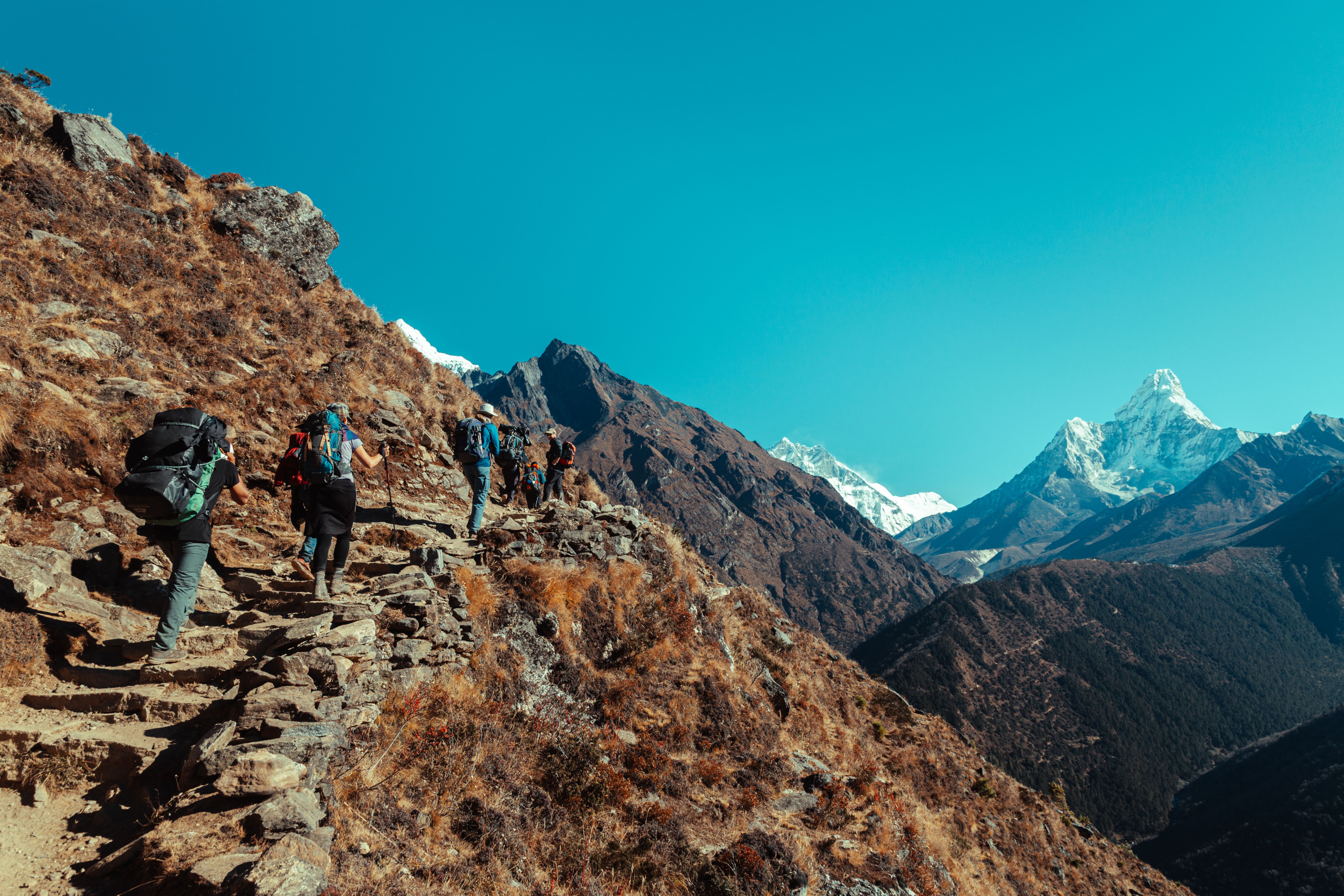 Group of hikers climbing rocky trail with stunning Himalayan views in Nepal.