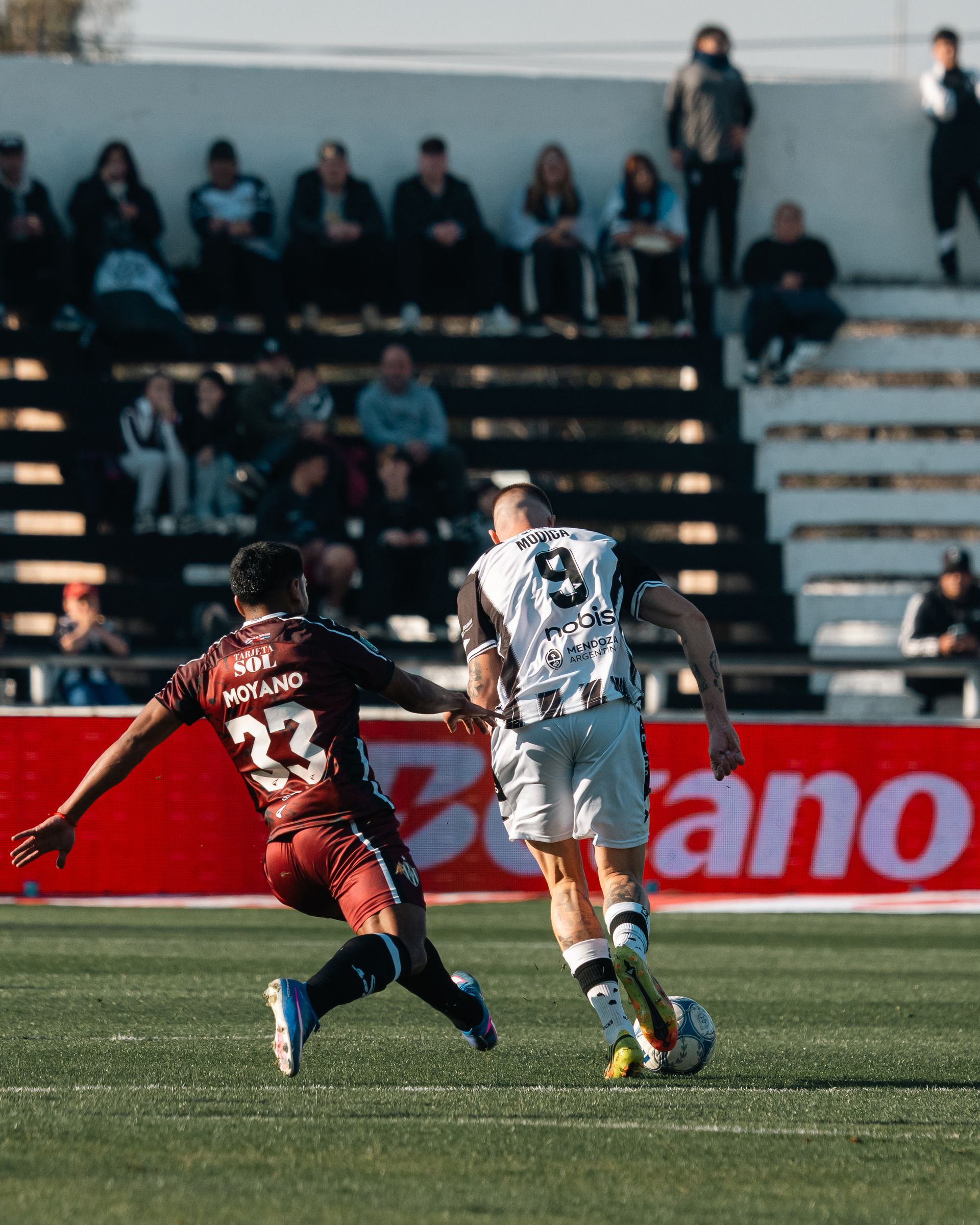 Two players vying for the ball in front of the stand