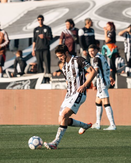 Free Soccer player controls the ball during a competitive match with crowd in the background. Stock Photo