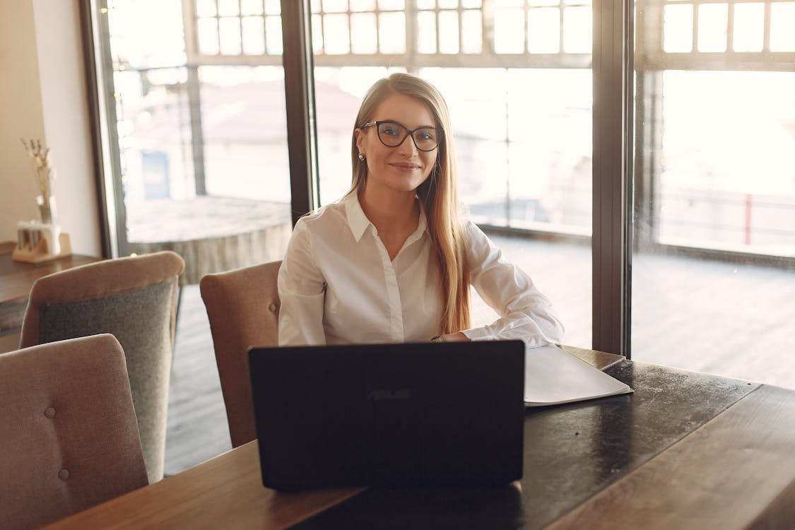 Free Woman in White Polo Shirt Sitting  In Front Of A Black Laptop  Stock Photo