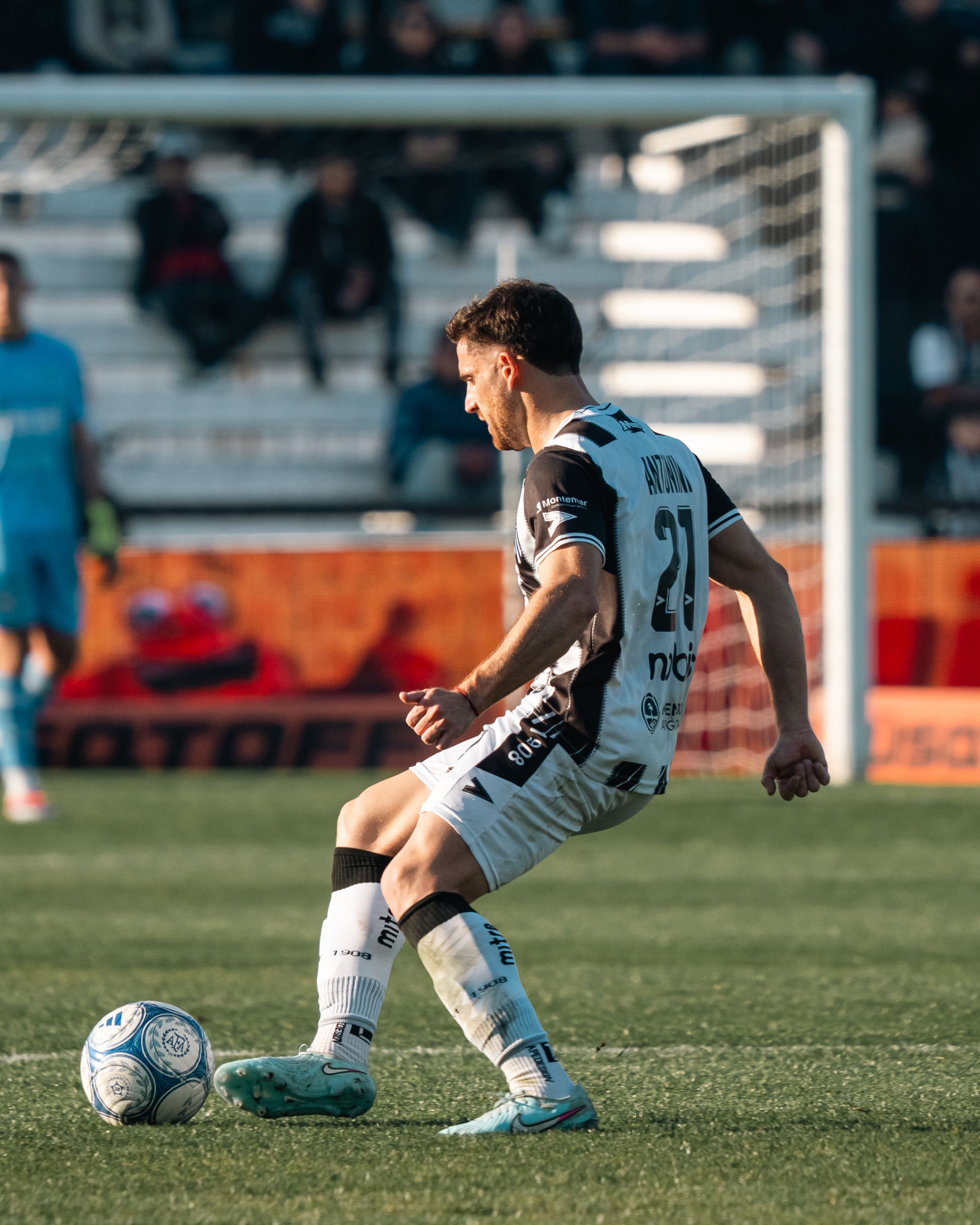 Soccer player in action on the field during a professional match on a sunny day.