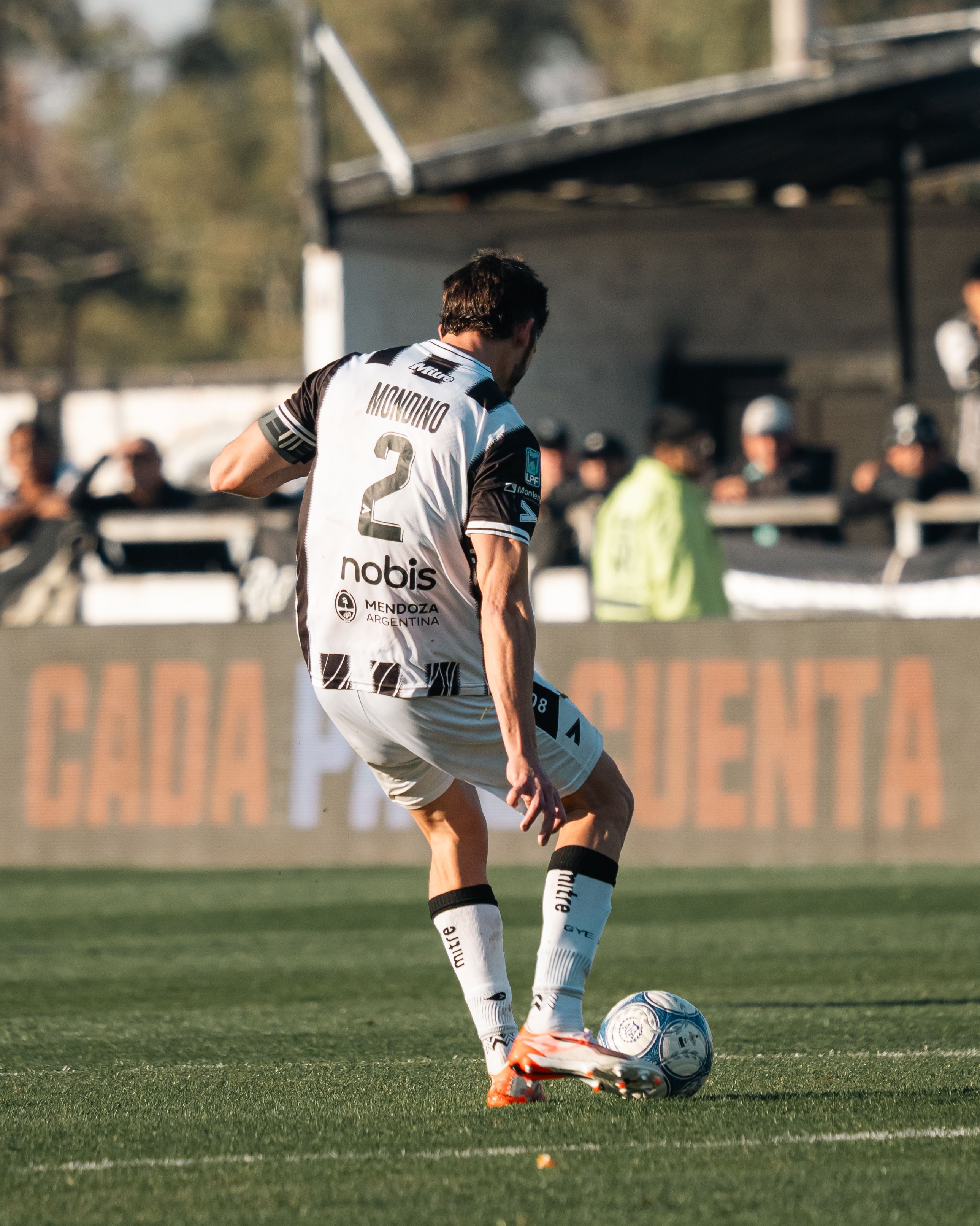 Professional soccer player dribbling during a daytime outdoor match.