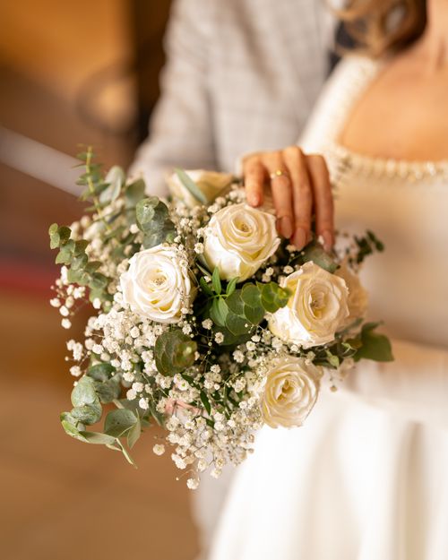 Free A close-up of a bridal bouquet with white roses and greenery at an indoor wedding. Stock Photo