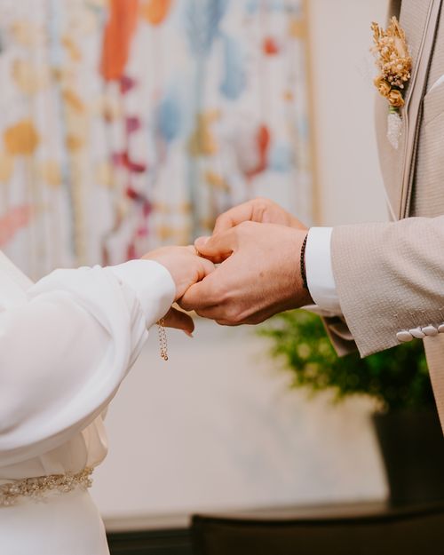 Free Close-up of hands exchanging wedding rings during a romantic indoor ceremony. Stock Photo