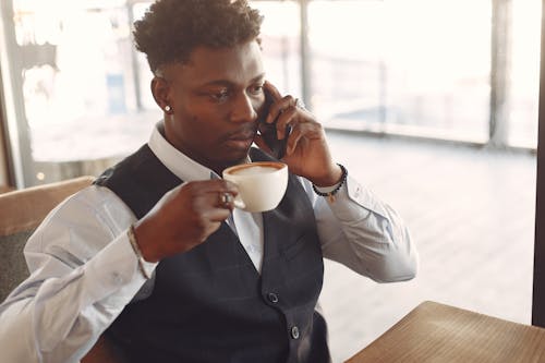 Man Drinking Coffee While Having Conversation Over The Phone