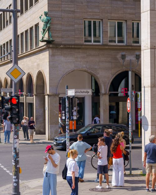 Free Street view of a busy intersection in Berlin with numerous pedestrians and city architecture. Stock Photo