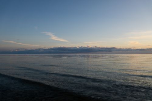 Free Serene ocean view at twilight capturing calm waters and soft clouds. Stock Photo