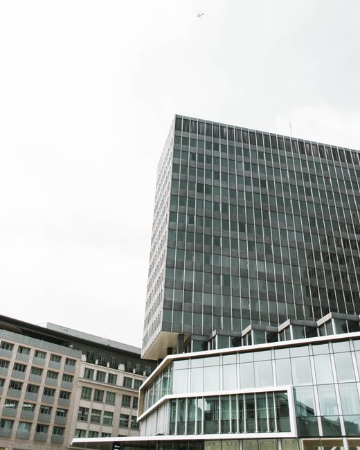 High-rise office buildings in Brussels with a plane flying overhead, creating a dynamic urban scene.