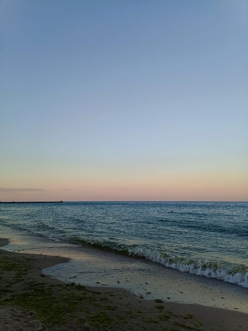Free Peaceful beach scene at sunset with gentle waves and a tranquil horizon. Stock Photo