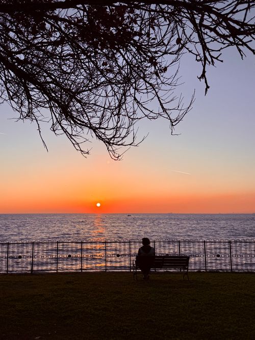 Free A person sitting on a bench watching a beautiful sunset over the Bosphorus in İstanbul, Türkiye. Stock Photo