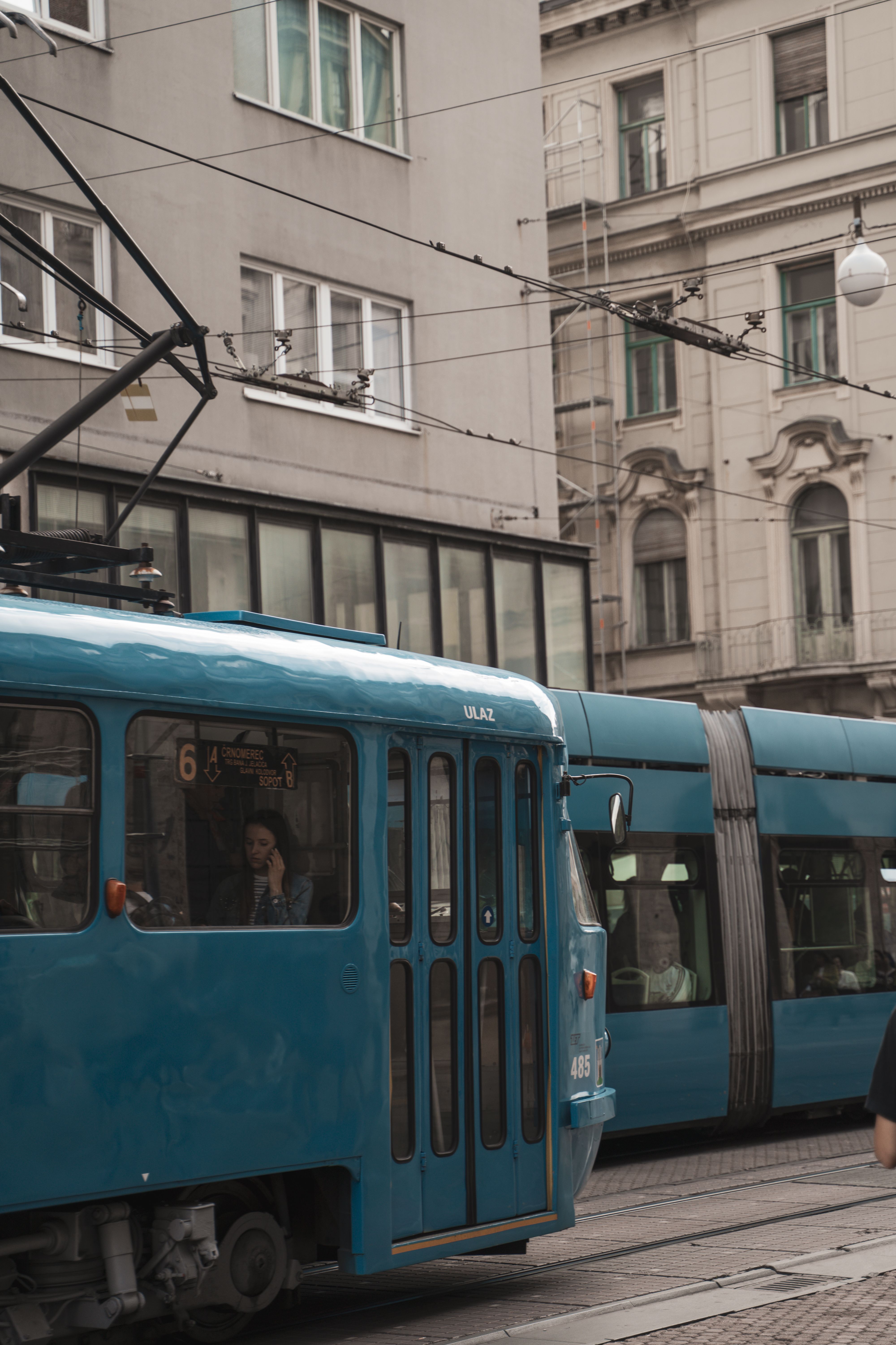 Blue trams traversing through a bustling European downtown area.