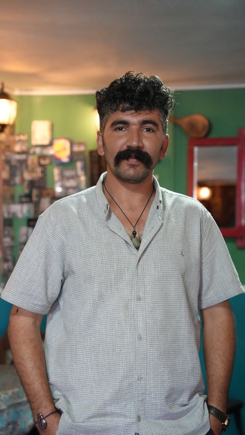 Free A middle-aged man stands confidently in a cozy cafe in Naqadeh, Iran, captured with warm ambiance. Stock Photo