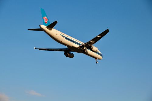 Free A commercial airplane flying against a clear blue sky background, with visible landing gear. Stock Photo