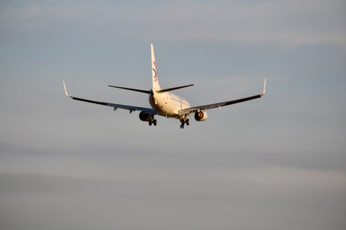 Free An airplane descends for landing against an evening sky, viewed from behind. Stock Photo