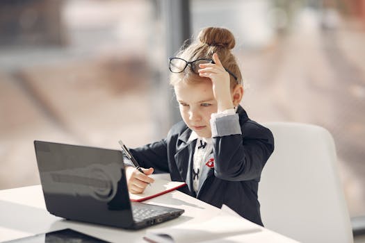A young girl dressed in business attire using a laptop, symbolizing childhood ambition and learning.