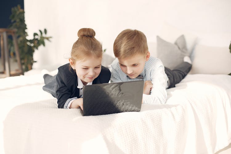 Positive Business Kids Using Laptop Together In Bedroom