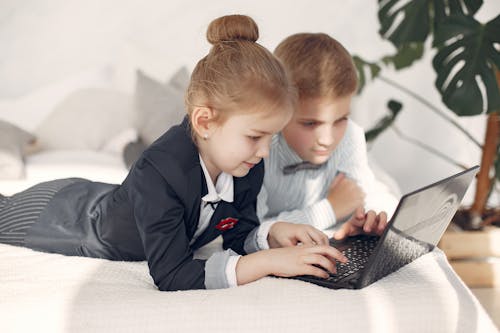 Smart little business children in formal outfits working with laptop remotely in team
