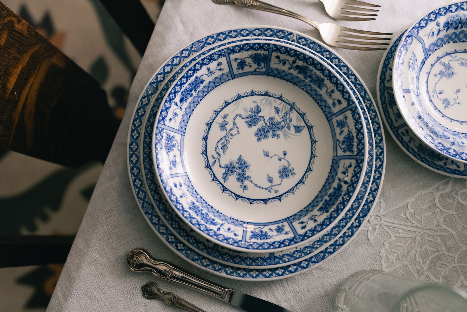 A classic dining setup featuring blue floral-patterned china on a white tablecloth, ready for a meal.