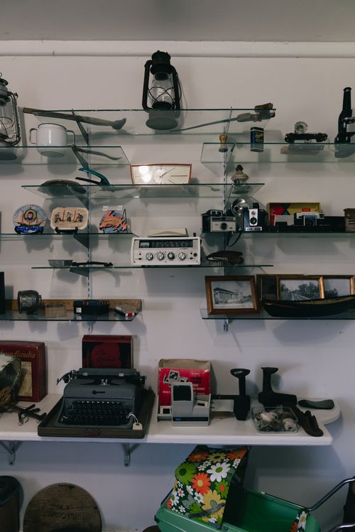 Free A diverse collection of vintage items including typewriters and cameras displayed on glass shelves in a cozy setting. Stock Photo