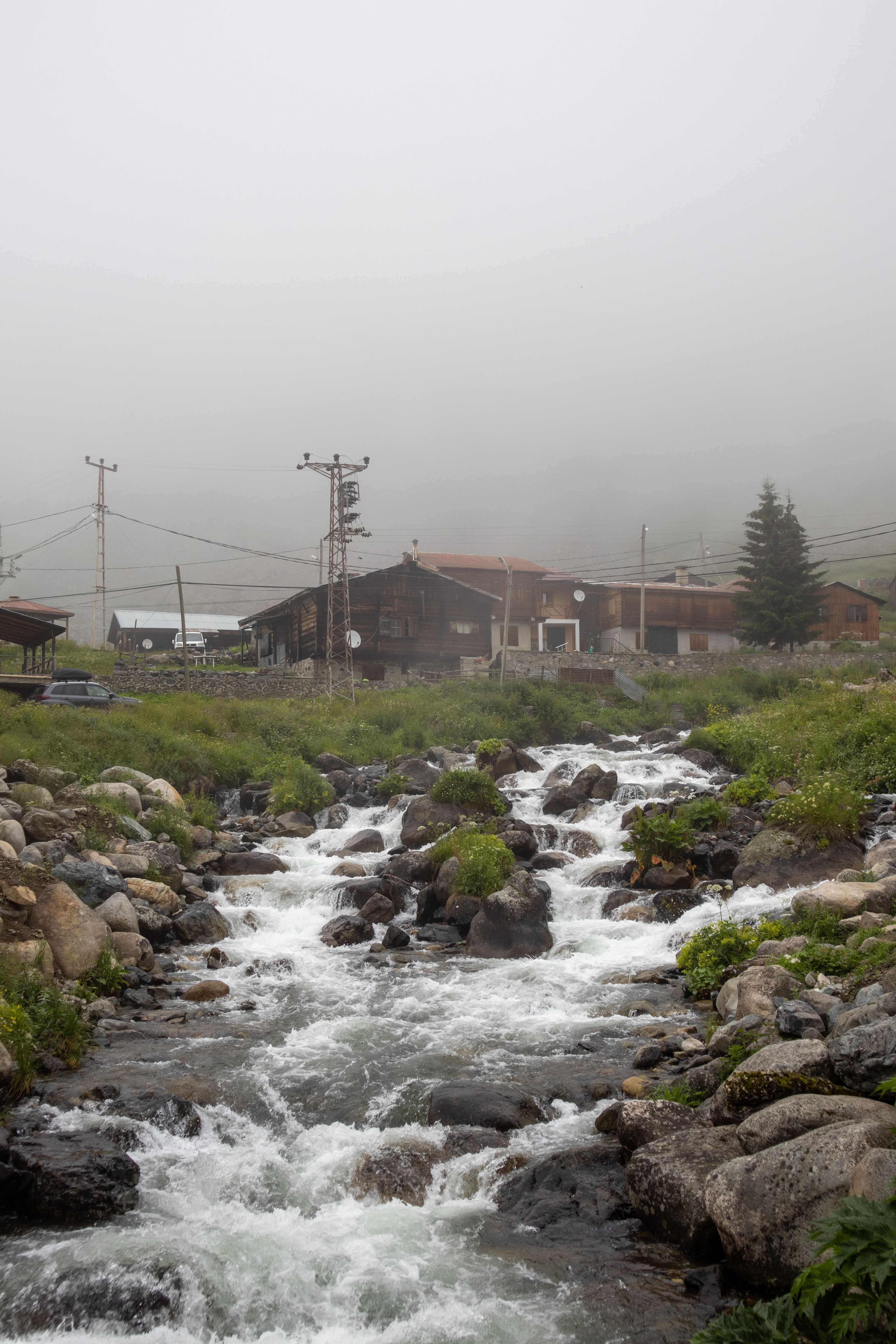 Scenic view of a mountain stream in Rize, Türkiye with fog enveloping the landscape.