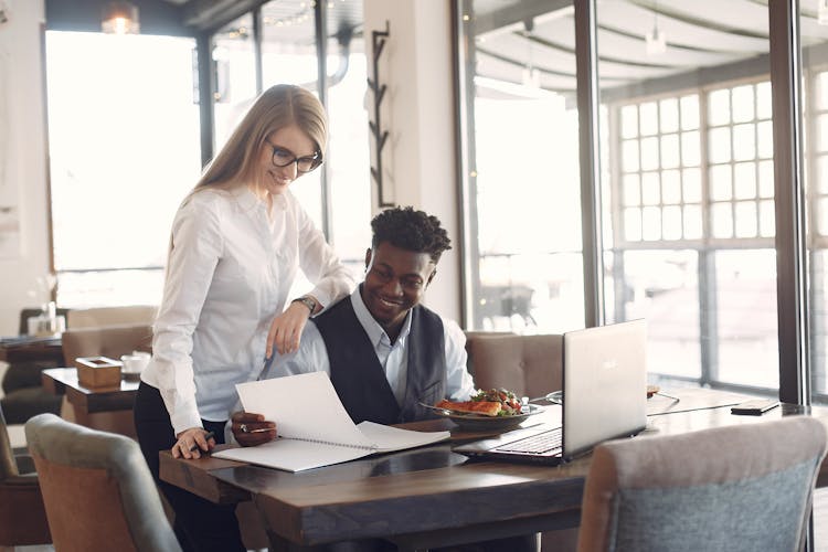 Young Cheerful Business People Working Remotely In Cafe During Lunch Break