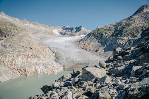 Free A stunning view of an alpine glacier surrounded by rocky mountains under a clear blue sky. Stock Photo
