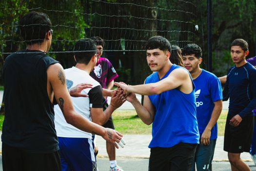 A group of young men playing volleyball outdoors in Ciudad de México, showing teamwork and sportsmanship.