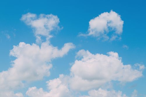Free Serene view of fluffy white clouds floating in a clear blue sky, ideal for backgrounds. Stock Photo