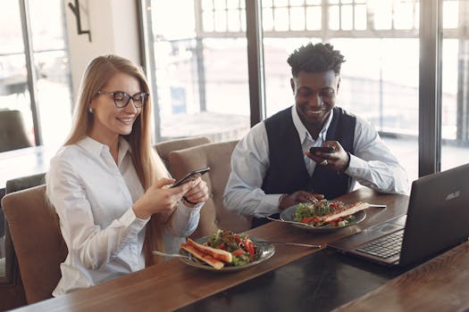 Business colleagues enjoying lunch while using smartphones in a modern café setting.