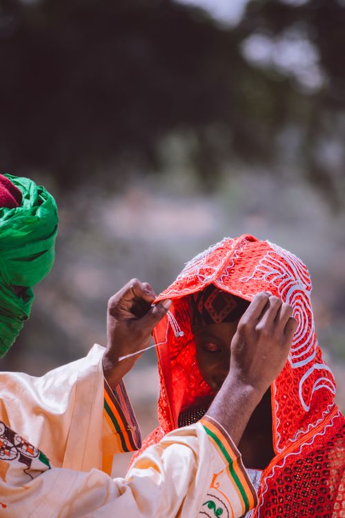 Free Two people engaged in a traditional ceremony, wearing colorful, vibrant attire outdoors. Stock Photo