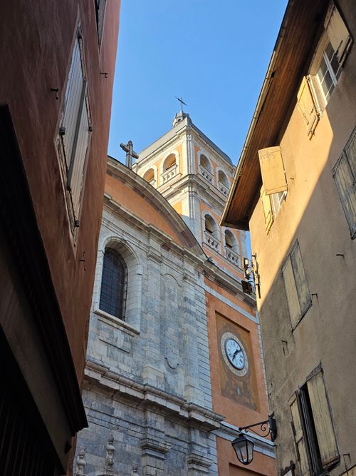 Free View of a historic church facade and bell tower through a narrow sunlit alley. Stock Photo