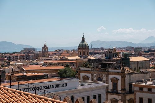 Free Captivating view of Palermo's historic architecture against a mountainous backdrop under a clear sky. Stock Photo