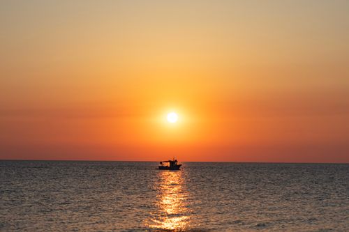 Free A serene sunset view over the Mediterranean Sea with a lone boat near Cefalù, Sicily. Stock Photo