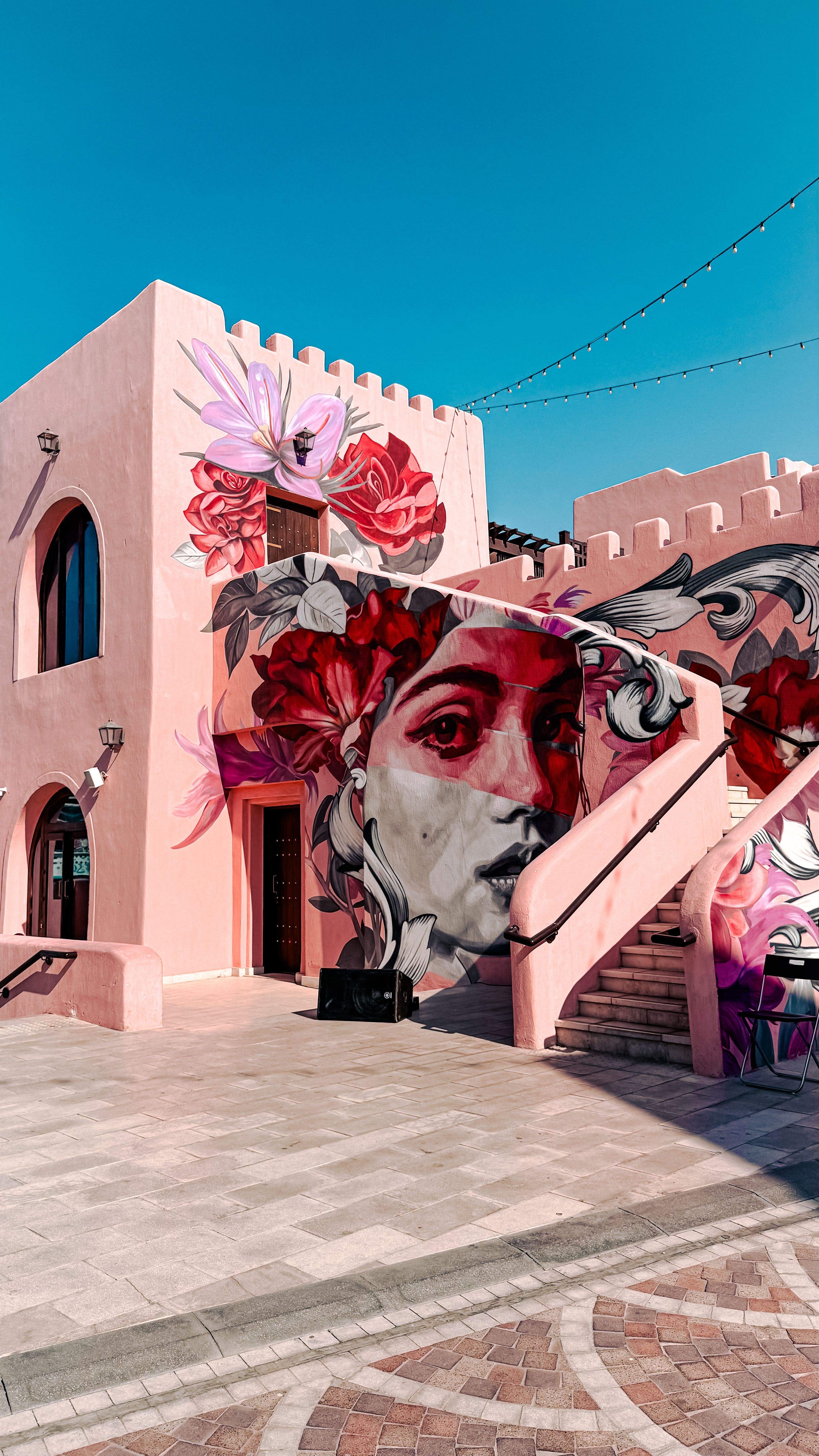 Vibrant mural of a woman's face with floral patterns on a building in Dubai's street art scene.