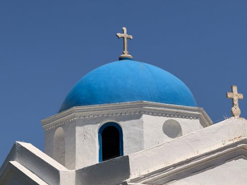 Free Iconic Greek architecture featuring a white church with a striking blue dome under clear skies. Stock Photo
