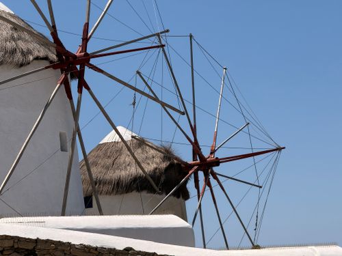 Free Traditional windmills of Mykonos, Greece, with their distinctive thatched roofs and white walls against a clear blue sky. Stock Photo
