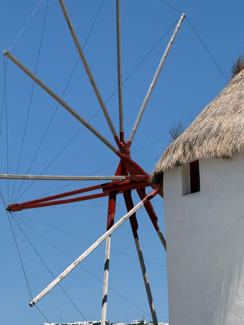 Free Iconic white windmill with red sails under a clear blue sky in Mykonos. Stock Photo