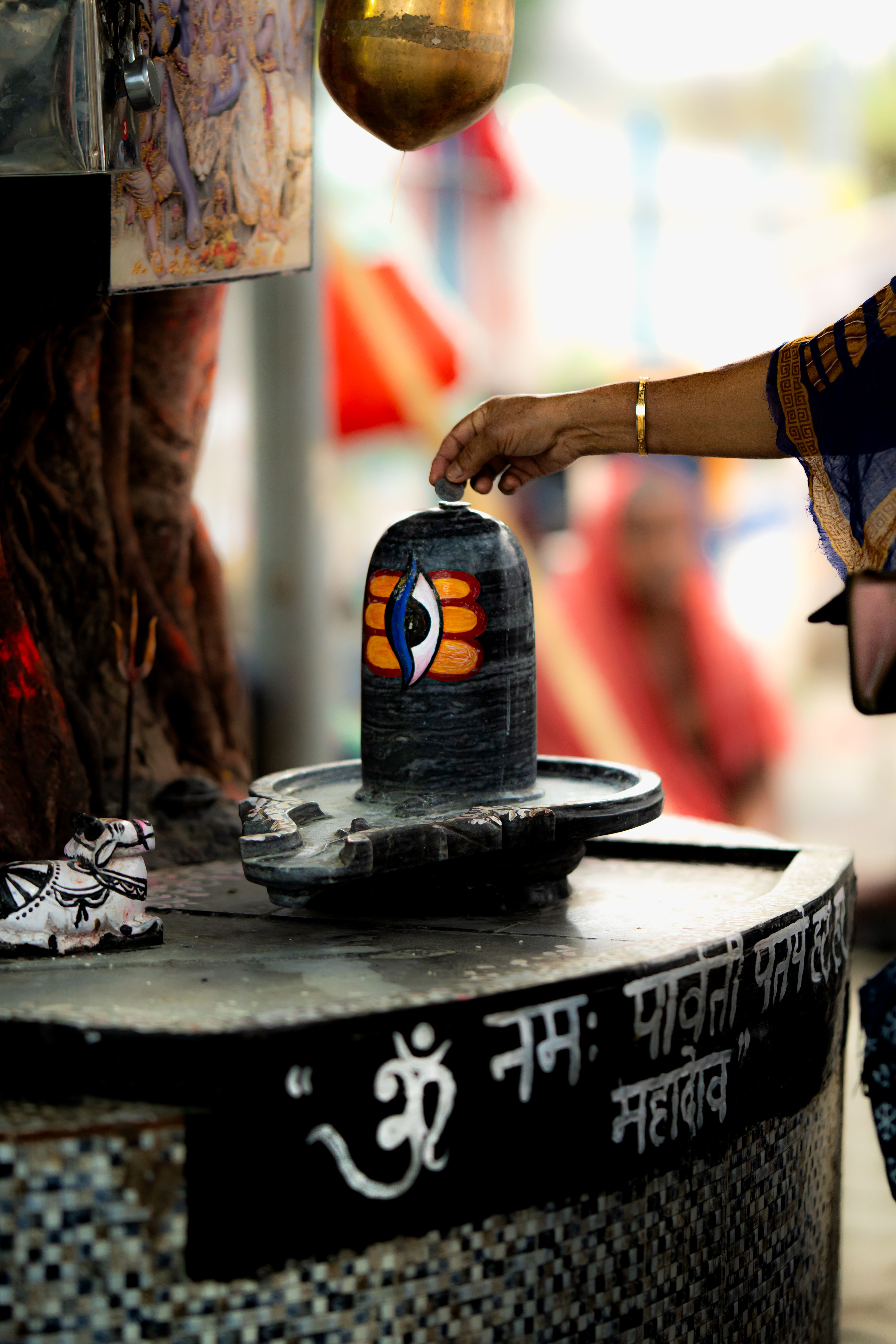 A devotee's hand offering to Shiva Lingam at a temple in Kolkata, India, symbolizing spiritual devotion.
