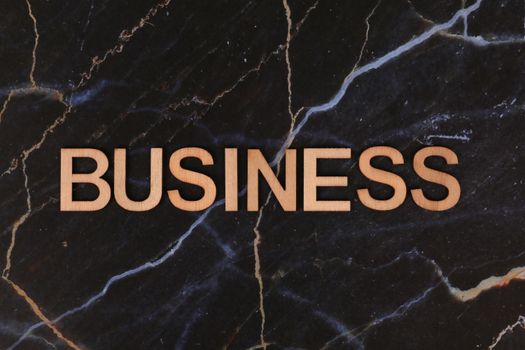 Wooden 'Business' text on a stylish dark marble surface, ideal for corporate design.
