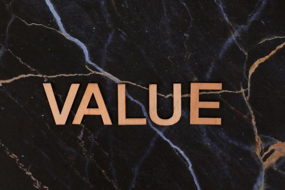 A close-up of wooden 'Value' letters placed on a dark marble background, emphasizing texture and concept.