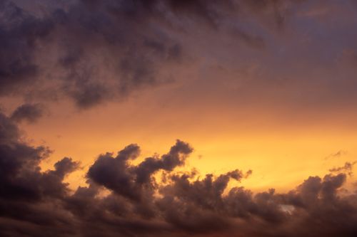 Free A vibrant sunset sky filled with dramatic, dark clouds casting a moody atmosphere. Stock Photo