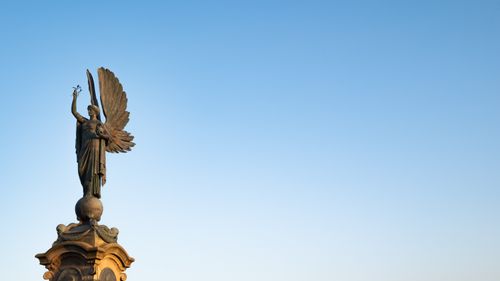 Free Angel statue with wings in Brighton, UK, set against a clear blue sky. Stock Photo