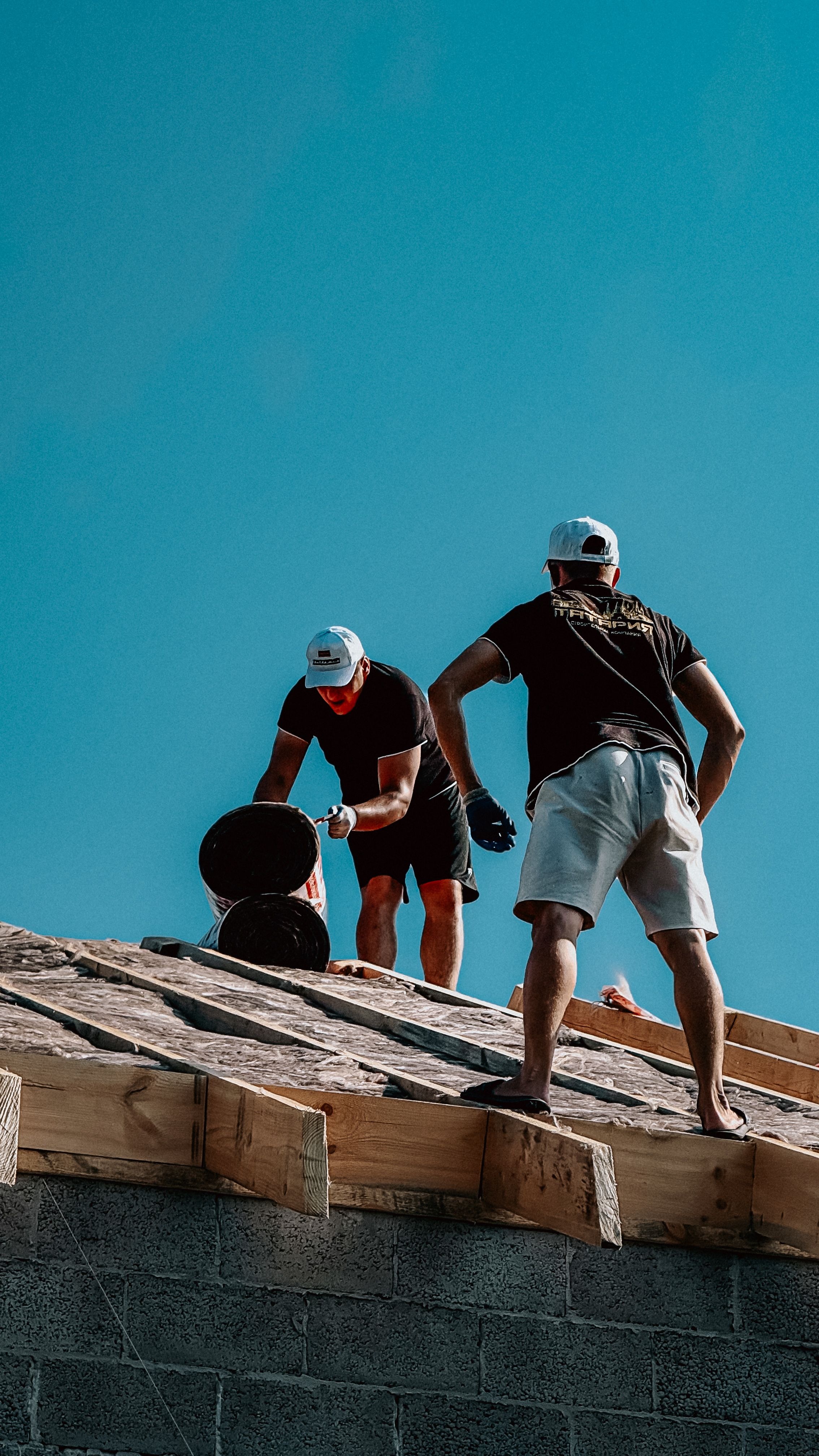 Roofing and waterproofing materials UAE - construction workers applying roofing membrane under clear sky representing B2B roofing and waterproofing materials sourcing