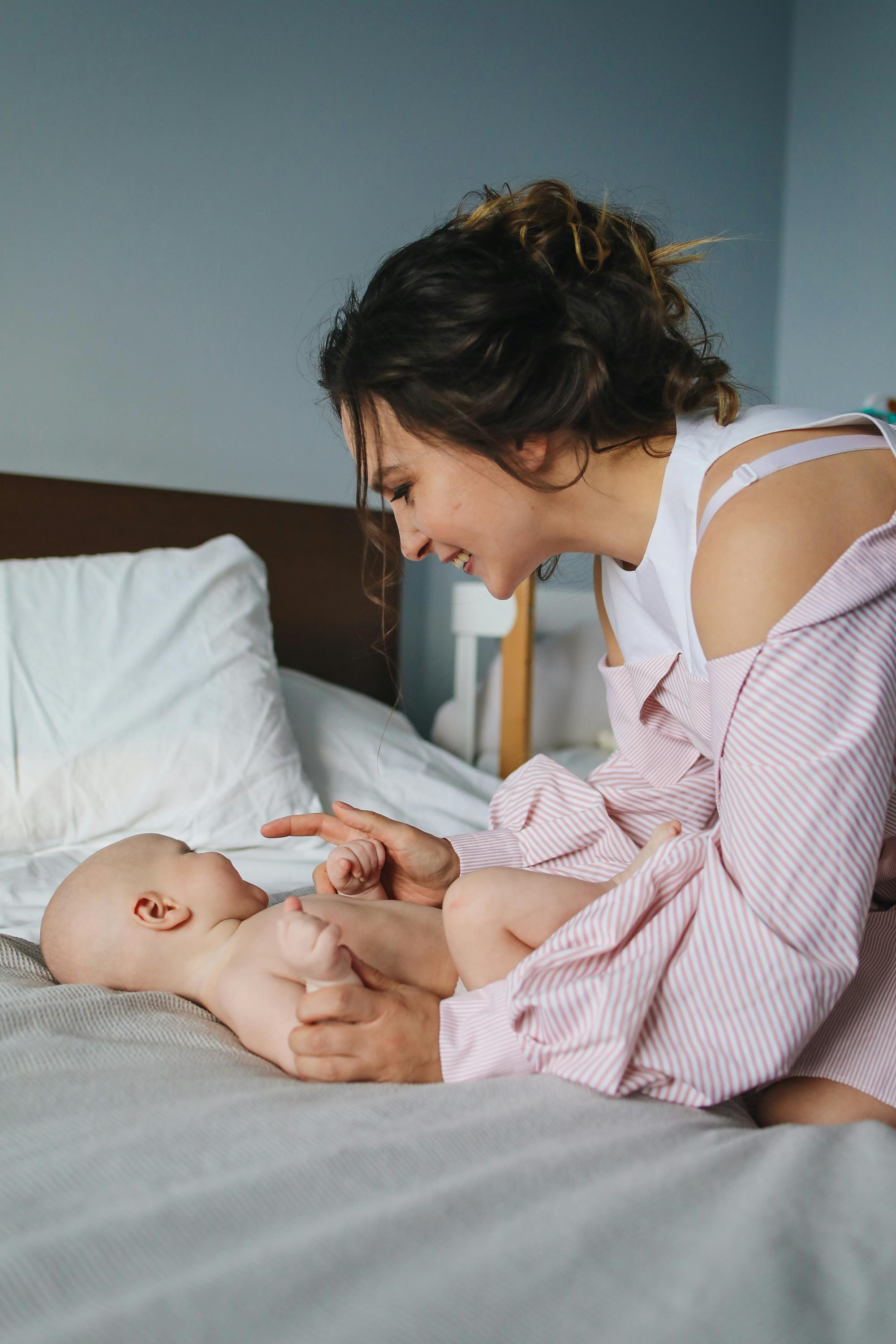 smiling mother playing with her baby on bed