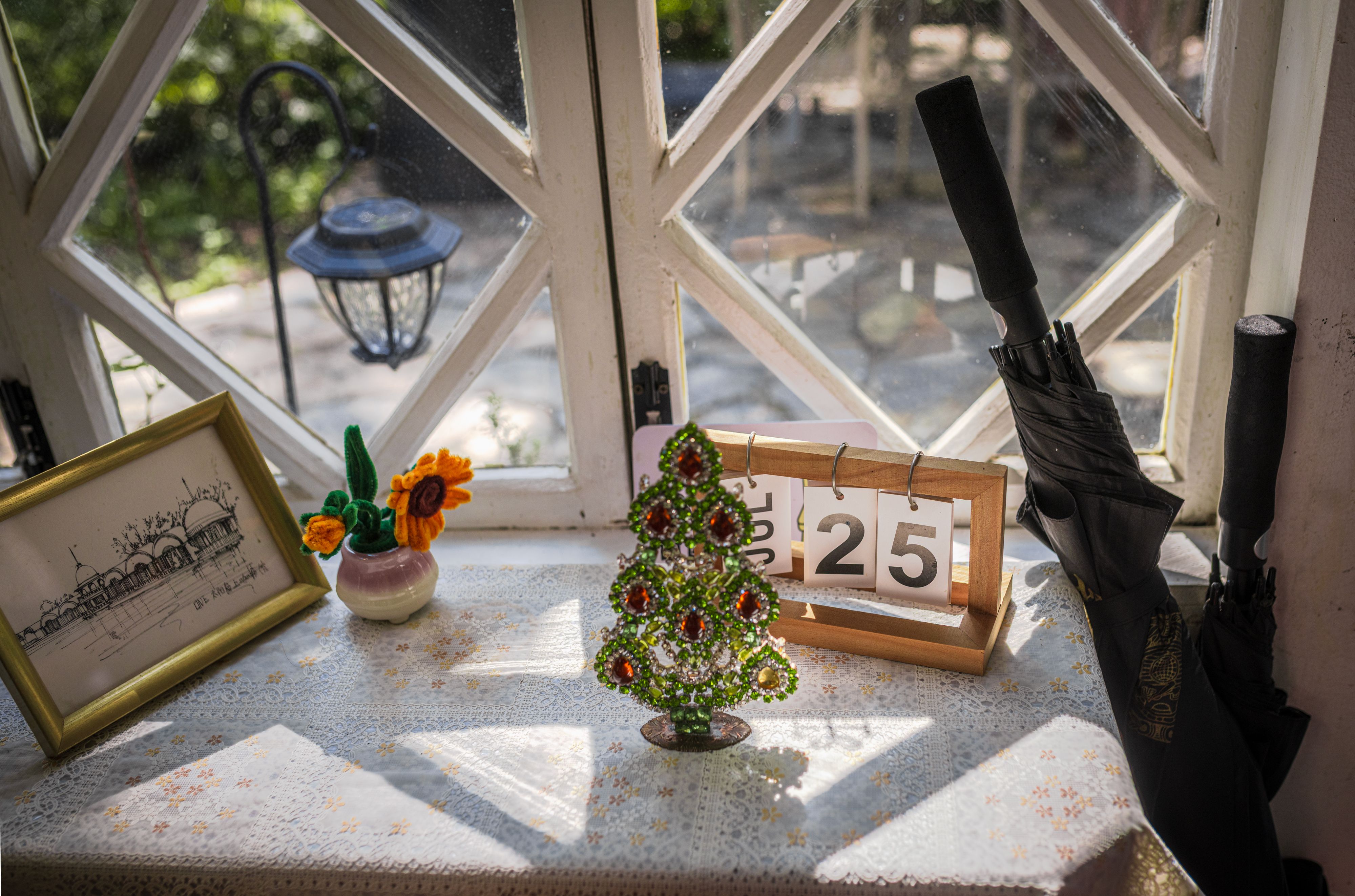 Charming table by window with mini Christmas tree, calendar date, and artistic decor.