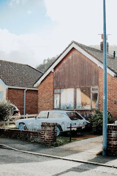 一辆旧车停在砖房前，晴朗的天空下，捕捉到宁静的郊区氛围