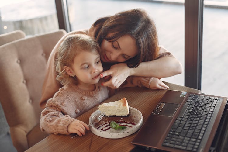 Mother And Daughter With Laptop In Cafe