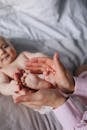 特写镜头中，父母的手在室内床上轻轻握住婴儿的脚