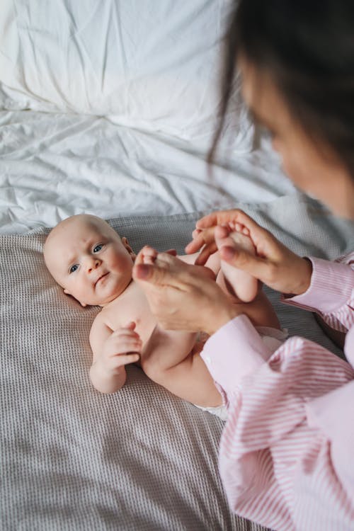  Person in White and Pink Striped Long Sleeve Shirt Holding Baby's Feet