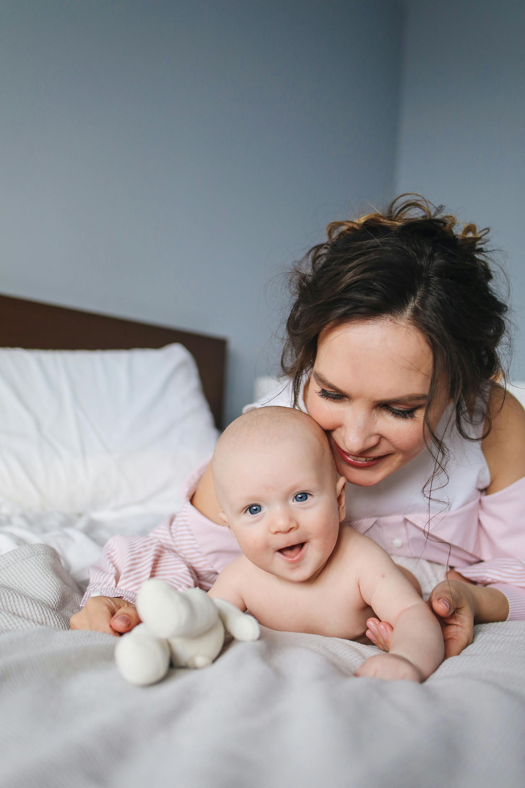 smiling mother playing with her baby on bed